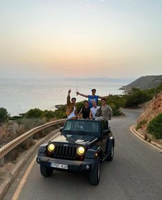 four people are riding in the back of a jeep with their arms up and one person is waving