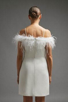 the back of a woman's white dress with feathers on her shoulder and shoulders