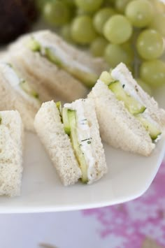 several sandwiches are arranged on a plate with grapes