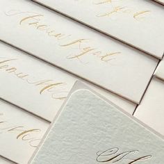 white envelopes with gold calligraphy are lined up on top of eachother