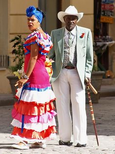 a man and woman dressed in colorful clothing standing next to each other on the street