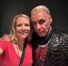 a man and woman posing for a photo in front of a black background, with their arms around each other