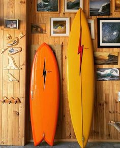 two surfboards are standing next to each other in front of pictures on the wall