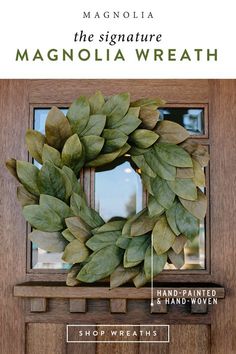 a wreath is hanging on the front door next to a red apple and green leaves