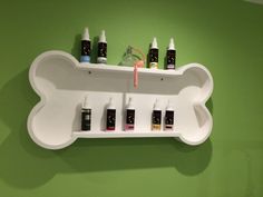 a white shelf with five different types of skin care products on it against a green wall