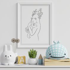 a drawing of a woman holding a baby in her arms is displayed on a shelf