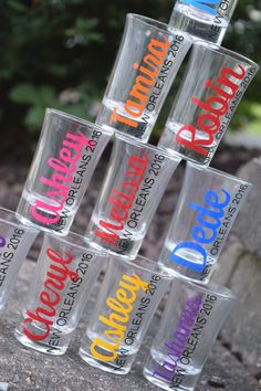 a stack of clear cups with different colored lettering on them sitting in front of some trees