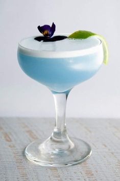 a blue and white drink with a flower on the rim, garnished with a green leaf