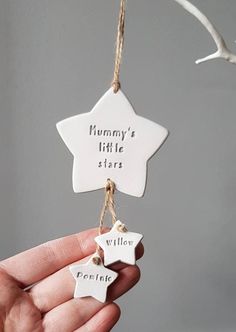 a person holding up a white ceramic star ornament with words written on it