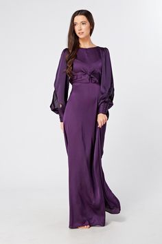 Description Composition Size This stylish purple maxi dress with wide long sleeves is a refreshing new addition to the ladies' wardrobe. The soft and lavish crepe fabric is very light and smooth. The wide skirt flows gracefully from the waist down to elongate the legs. And the top fits perfectly on the shoulders and gives a flawless accentuated upper body.  Shape: Fitted and Maxi Sleeves: Floating Long Sleeves. Purple Button Closure with Big Cuffs Colour: Purple Length: 60 inches or 152 cm (Our model is 168 cm and wearing a size S) Skirt Style: Flowy and Maxi Top Style: Knotted on front and button on back  Neckline: Closed neckline Pattern: Crepe  Zipper: Hidden Zipper Closes at The Side, Elasticated back Fabric: 95% Polyester, 3% Viscose, 2% Nylon. The fabric is very light and airy Occasi High Neck Bridesmaid Dresses, Crepe Maxi Dress, Wide Skirt, Bridal Party Attire, Purple Maxi, Purple Maxi Dress, Maxi Tops, Dress Design Sketches, Dresses Xxl