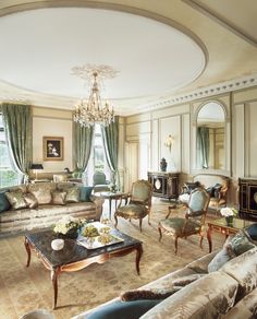 a living room filled with furniture and a chandelier in the middle of it