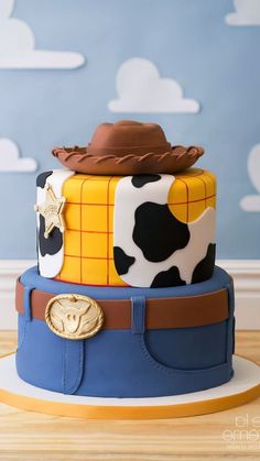 a three tiered cake with toy story characters on it's sides and a cowboy hat on top