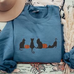 This unisex cozy Gildan sweatshirt is embroidered with adorable black cats amidst pumpkins :)  * 50% cotton, 50% polyester * Pre-shrunk * Classic fit * 1x1 athletic rib knit collar with spandex * Air-jet spun yarn with a soft feel and reduced pilling * Double-needle stitched collar, shoulders, armholes, cuffs, and haem SIZING: Please ensure you check measurement chart before ordering as shirts are embroidered once you place your order. Sweatshirts are unisex sizes but they fit true to size for l Fall Crew Neck Sweatshirt With Cat Design, Casual Cat Design Sweatshirt For Fall, Mom Crewneck, Sweatshirts For Women, Cat Pumpkin, Cat Sweatshirt, Gildan Sweatshirts, Fall Shirt, Measurement Chart