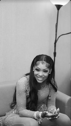 a woman sitting on top of a couch in front of a lamp and smiling at the camera