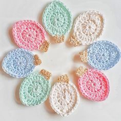 six crocheted ornaments arranged in a circle on a white surface with gold accents