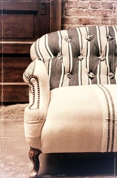 a striped couch sitting on top of a wooden floor next to a brick wall and door