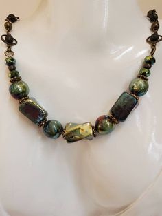 This necklace features ceramic (raku) rectangular and round shaped beads. They have a glossy finish that almost look metallic! The colors are green and gold with some purple undertones. Watch the video to see the beauty of these beads!!  Let's talk about the chain on this neckace; it's called 'saturn chain'. There are round antique copper color beads alternating with every other bead having a halo around them. I love love love this chain and it is so hard to find! The necklace measures 16 inches Ceramic Beads Necklace, Japanese Jewelry, Earthy Jewelry, Color Beads, Japanese Pottery, Green Ceramics, I Love Love, Ceramic Beads, Copper Color