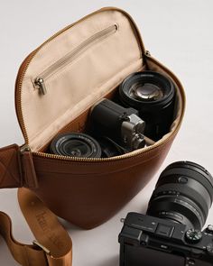 a camera and some other items in a brown leather case on a white table top