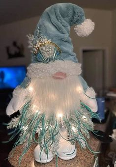 a gnome figurine sitting on top of a table next to a christmas tree