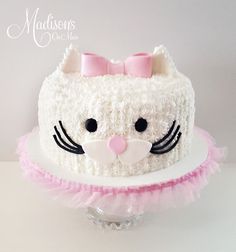 a cake decorated with white frosting and pink icing has a cat's face on it