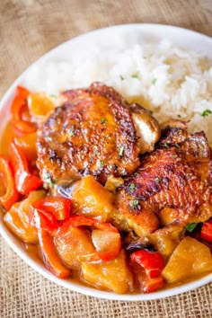 a white bowl filled with meat and vegetables next to rice on top of a table