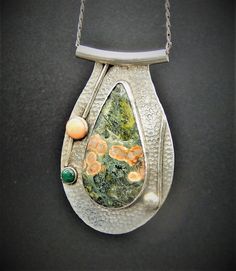 Hammered sterling silver pendant sports a large, fascinating and rich green and peach ocean jasper.  The stone is surrounded by sterling wire and coral and malachite stones and a larger sterling orb.  The piece is topped by a large sterling tube with a substantial sterling link chain.  You definately won't see anyone else with this statement piece as it is an original artisan one of a kind item! Unique One-of-a-kind Ocean Jasper Jewelry, Artisan Green Ocean Jasper Jewelry, Unique Silver Ocean Jasper Jewelry, Distinctive Green Jasper Jewelry, Unique Green Jewelry With Large Pendant, Green Chrysocolla Jewelry With Large Pendant, Unique Jasper Jewelry With Large Pendant, Silver Ocean Jasper Necklace, Unique Silver Ocean Jasper Necklaces