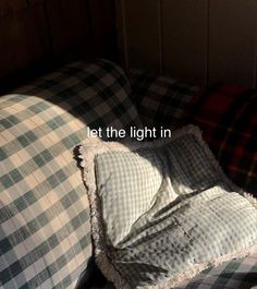 a plaid couch with the words let the light in written on it's pillow