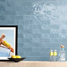 there is a blue brick wall with a painting on it and lemons in the foreground