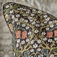 an ornately designed pillow with elephants on it's back and floral design in the background