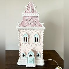 a pink and white clock tower sitting on top of a wooden table