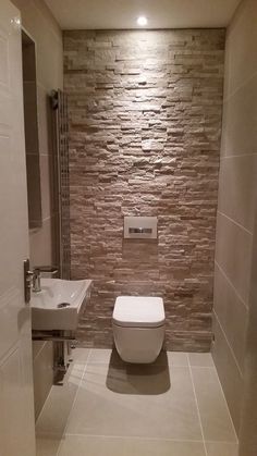 a bathroom with a toilet, sink and towel rack in the corner next to a brick wall