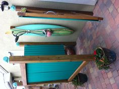 a surfboard mounted to the side of a wall next to flowers and potted plants