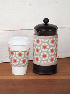 two coffee cups sitting next to each other on top of a wooden table with a white wall behind them