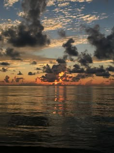 the sun is setting over the ocean with clouds in the sky and water below it