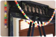 a mirror with some colorful beads on it and a black coat rack in the background