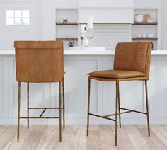 two brown leather bar stools sitting in front of a white kitchen counter with wooden floors