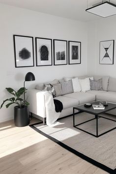 a living room with white furniture and pictures on the wall above it's coffee table