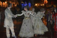 several people dressed in costumes dancing on the street