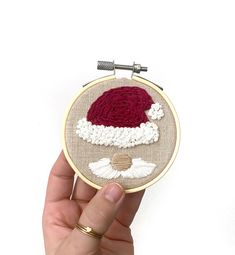 someone is holding up a hand embroidered santa hat