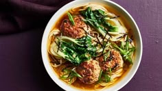 a bowl filled with meatballs and noodles on top of a purple table cloth next to a napkin