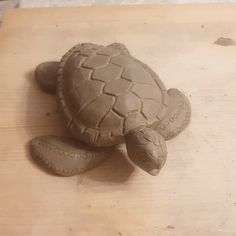 a clay turtle sitting on top of a wooden table