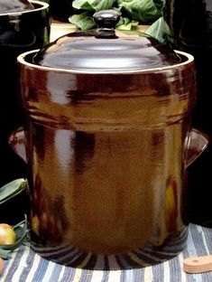 a large brown pot sitting on top of a table next to other pots and pans