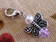 a key chain with a butterfly charm attached to it on a piece of fabric next to other items