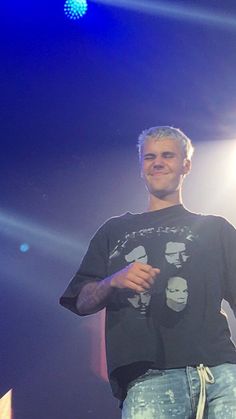 a man standing on top of a stage with his hands in his pockets and smiling