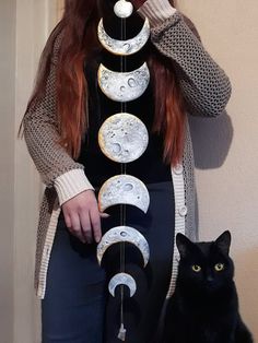 a woman standing next to a black cat and wearing a dress with phases on it