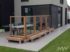 a patio with tables and chairs in front of a large glass doored building on the side of a road