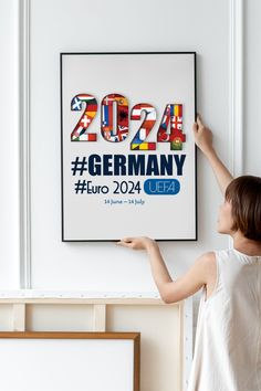 a woman is pointing to a poster on the wall that says germany in different languages