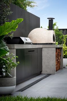 an outdoor bbq with grill, sink and potted plants