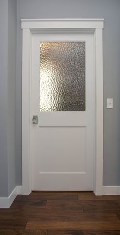 a white door in a gray room with wood flooring and glass panels on the window