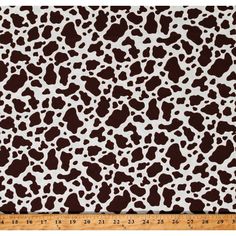 a brown and white animal print fabric with black spots on the side, in front of a ruler